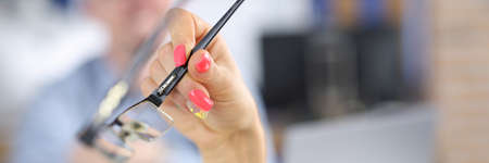 Womans hand with bright nails holds glasses