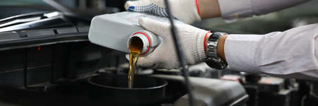 Foreman pours engine oil into engine closeupの写真素材