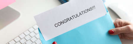 Woman sitting at table and holding letter with congratulations closeupの写真素材