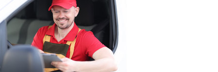 Man courier in uniform sitting at wheel of car with digital tablet in his hands