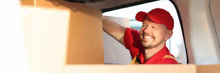 Male courier putting cardboard boxes in carの写真素材