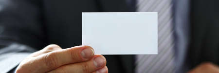Male arm in suit give blank calling card to visitorの写真素材