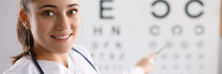 Woman doctor checking eyesight using table in clinic