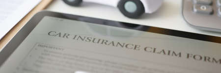 Digital tablet with car insurance form lying on table near toy car closeupの写真素材