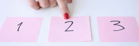 Woman showing index finger to sticker with number 2