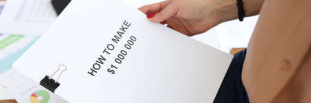Woman holding documents in her hands with title How to make 1 000 000 closeupの写真素材