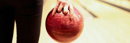 Woman throwing red bowling ball on lane closeup