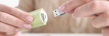 Woman hand inserts usb wire from smartphone into USB flash driveの写真素材
