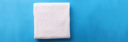 White terry towel is folded on blue background. Bathroom towel selection conceptの写真素材