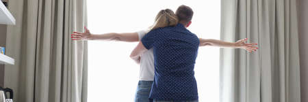 Man gently hugs awoman in hotel room next to suitcaseの写真素材