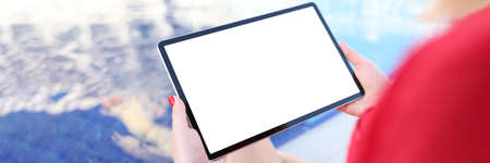 Young woman holding digital tablet with blank screen by pool