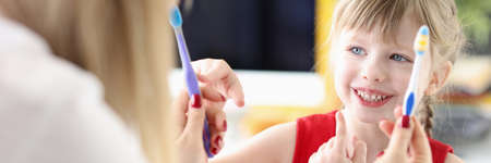 Little girl choosing toothbrush from doctors hands in clinicの写真素材