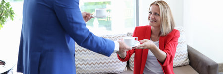 Man giving woman cup of coffee in officeの写真素材