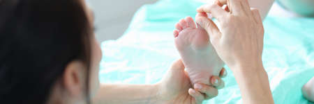 Podiatrist examining foot of small child in clinic closeupの写真素材