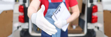 Male courier with documents giving his hand to client for handshake closeupの写真素材