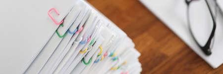 Lot of documents with colored paper clips lying on desktop closeupの写真素材