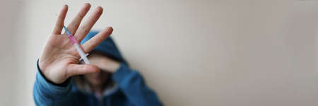Addict is holding syringe with needle in his handの写真素材