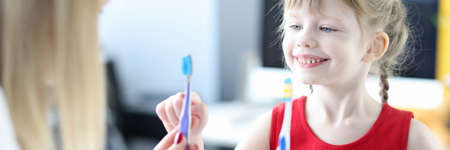 Dentist shows little girl two toothbrushes closeupの写真素材