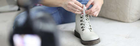 Woman blogger tying shoelaces on her shoes and filming closeupの写真素材