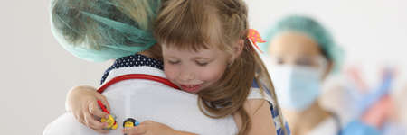 Nurse holding little girl with closed eyes in clinicの写真素材