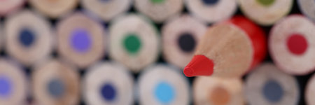 Red sharp wooden pencil lying closer multicolored blunt closeup background. Leadership skills...