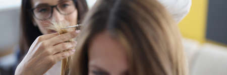 Young woman cutting ends of her hair with scissors to her friend at home closeupの写真素材