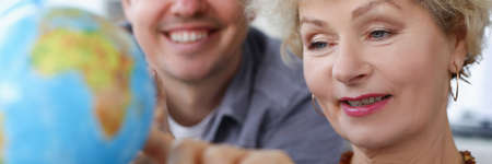 Elderly woman with her son is looking at globeの写真素材
