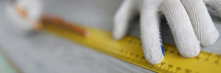 Hands of master making measurements with ruler on laminate