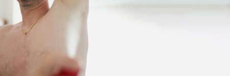 Man spraying antiperspirant against armpit sweat odor closeupの写真素材