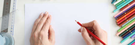 Female hands drawing on paper with colored pencils closeupの写真素材