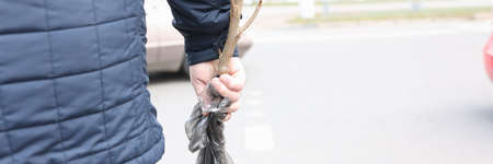 Elderly man carrying tree seedling in plastic bag closeup