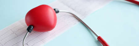 Red toy heart and stethoscope lying on cardiogram closeupの写真素材
