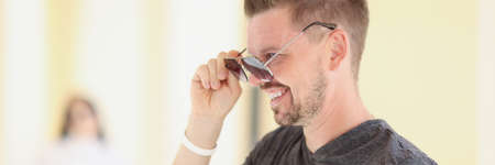 Young man with stylish hairstyle putting on sunglassesの写真素材