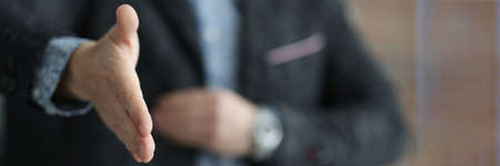 Man in black jacket stretching out his hand for handshake closeupの写真素材