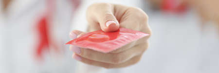 Doctor holding red condom in clinic closeupの写真素材