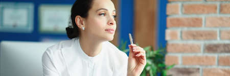 Portrait of young woman in office with pen in her handsの写真素材