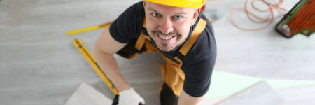 Carpenter in hard hat cutting laminate with electric saw top viewの写真素材