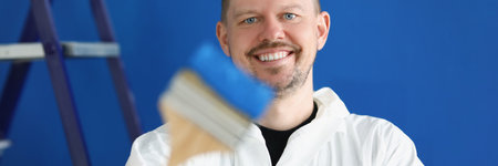 Portrait of young male construction worker in protective suit with paintbrush and paintの写真素材