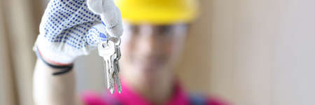 Woman builder in protective helmet holding keys in hands closeupの写真素材