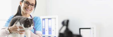 Woman veterinarian holding cat in front of camera in clinicの写真素材