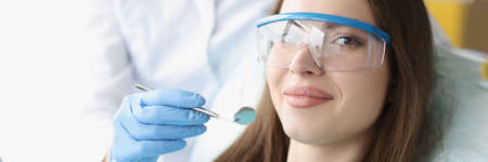 Portrait of young woman wearing safety glasses in dental chairの写真素材