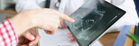 Woman doctor showing digital tablet with ultrasound picture of fetus in clinic closeup