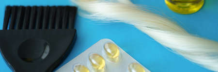 Vitamins and hair oil together with brush lie on dove backgroundの写真素材