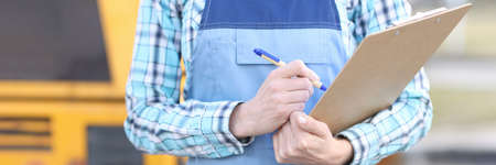 Woman builder in overalls holding clipboard and ballpoint pen closeupの写真素材