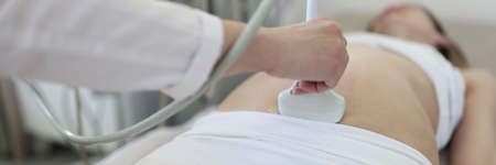 Doctor doing ultrasound scan of fetus to patient closeup