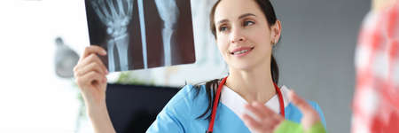 Doctor examines patient hand injury on an X-rayの写真素材