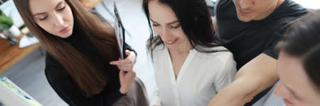 Group of students standing at blackboard and pointing finger at documentの写真素材