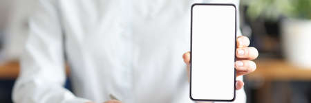 Business woman sitting at table with documents and showing mobile phone closeup