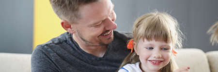 Smiling dad is holding little girl in his arms