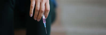 In female hand syringe with needle closeup